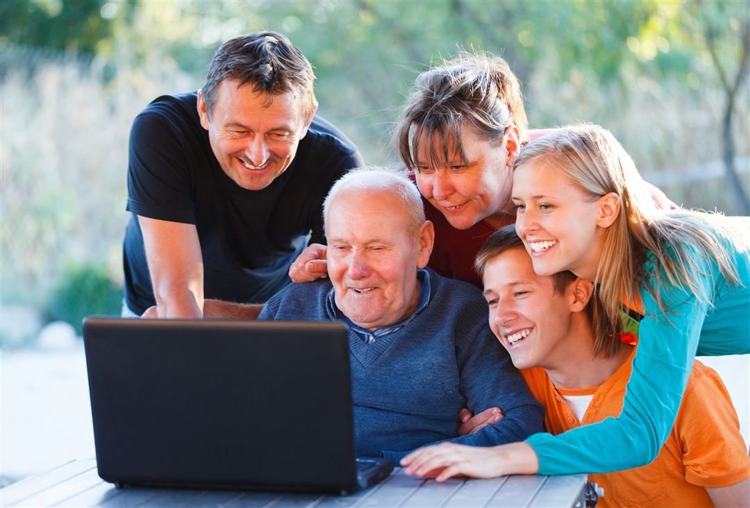 Familie schaut sich mit dem Großvater etwas Interessantes auf dem Laptop an